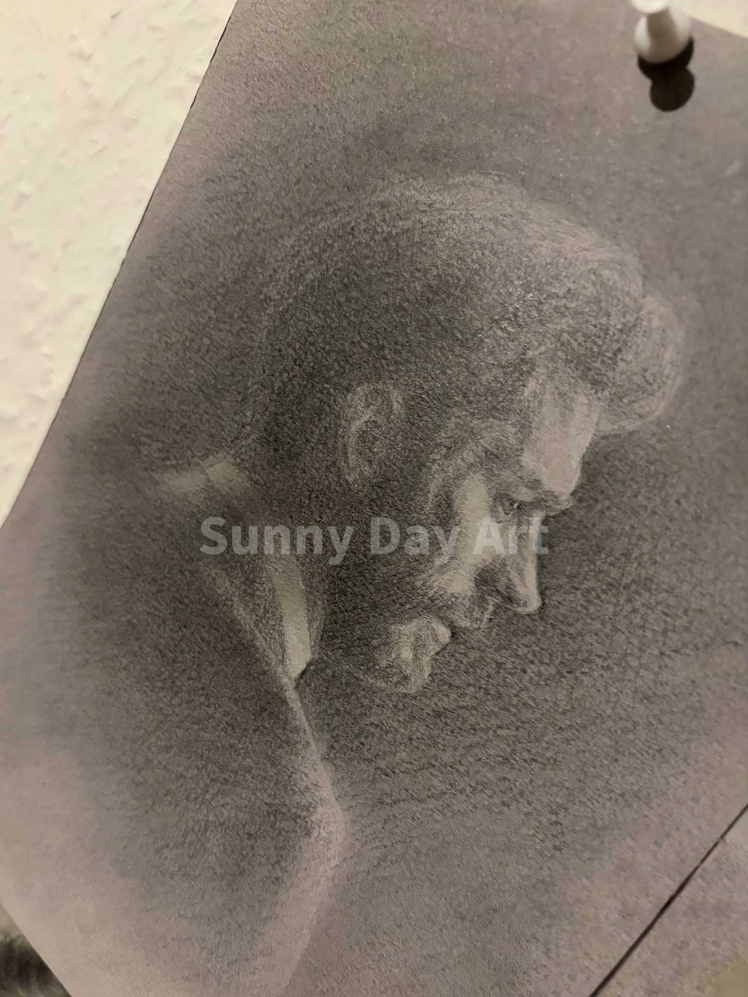 A sheet with a portrait pinned to a wall with a pushpin.