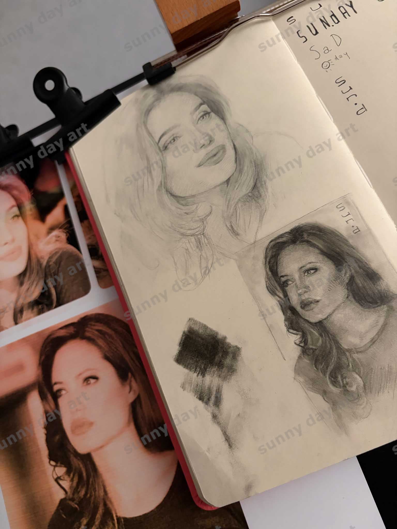 A sketchbook page featuring two sketches of Angelina Jolie—one graphite and one charcoal and graphite—taken from an angle.